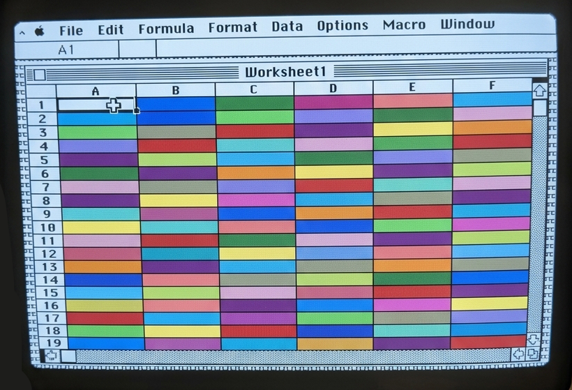 A classic Macintosh spreadsheet titled Worksheet1 with every cell filled in a different bright color
